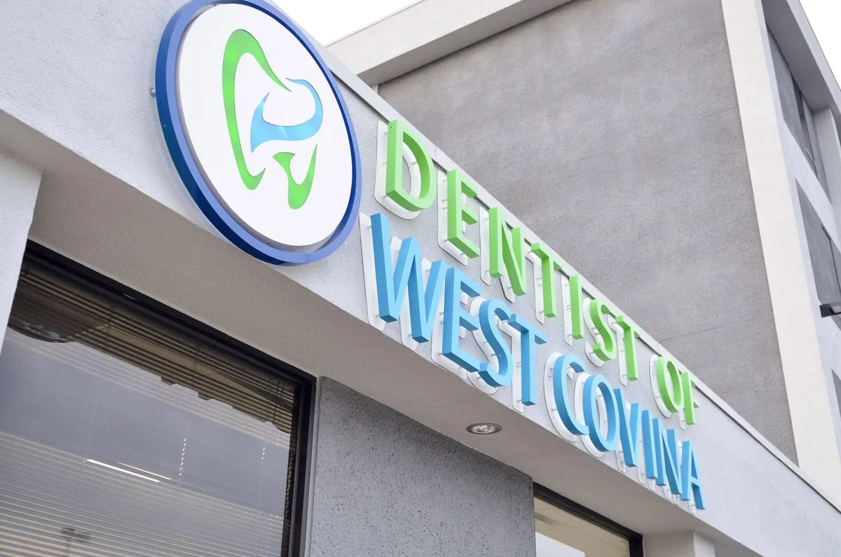 Exterior sign reading Dentist of West Covina displayed on the front of a modern dental office building.