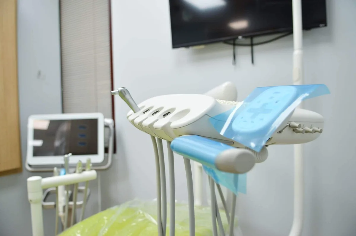Close-up of modern dental tools and controls with protective covers inside a clean treatment room.